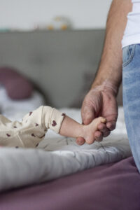 Nahaufnahme von Vaterhand die Babyfüße hält – Papa-Kind Bonding Foto